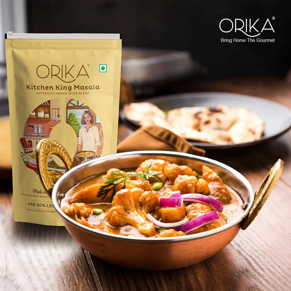 Orika Kitchen King Masala package with a bowl of curry on a wooden table